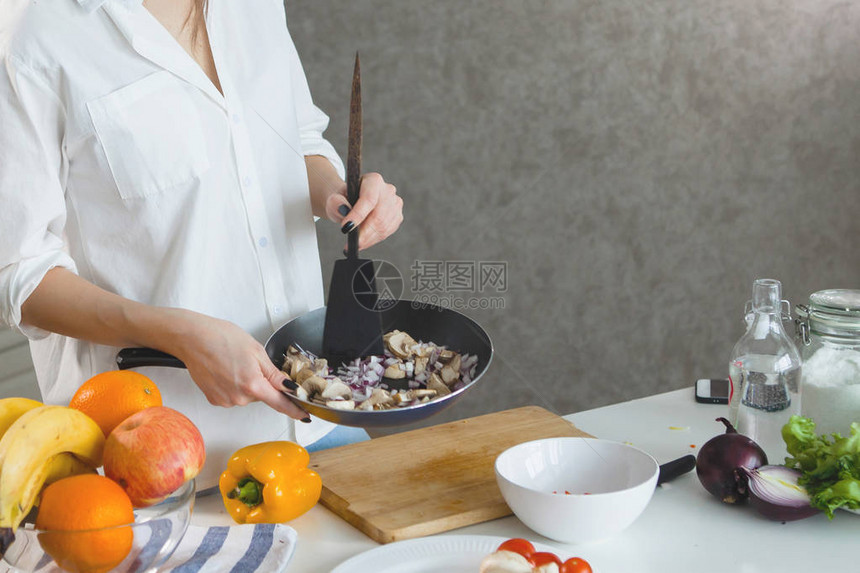 厨房里一个穿白衬衫的年轻美女手里拿着一根黑图片