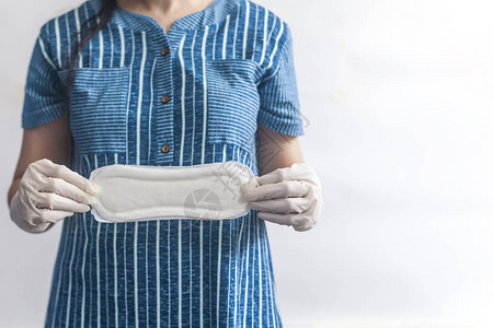 女卫生用品拿着卫生巾的医疗手套的妇女反对白色背景显示女月经周期图片