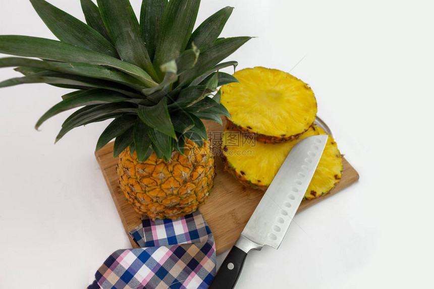 在木板上用切片刀和餐巾纸拍摄四分之三的菠萝图片