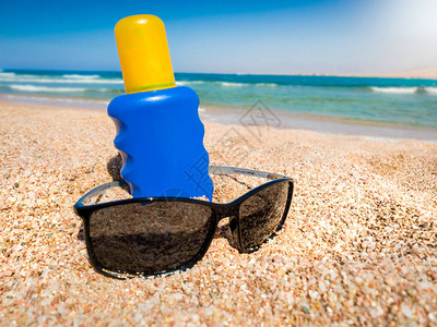 蓝色瓶子和太阳镜中的紫外线防晒液贴近镜头图片
