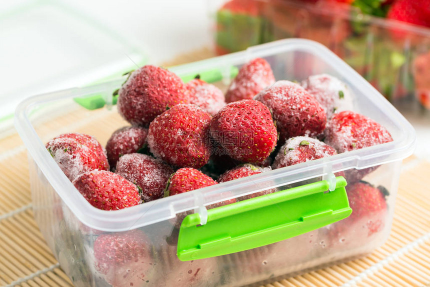 塑料盒中冷冻草莓的特写图片
