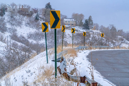 冬季山路方向路标被毁坏的公路经过一座满是房屋的雪盖的山图片