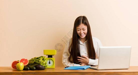 与笔记本电脑一起工作的年轻营养主义者妇女笑得开心图片