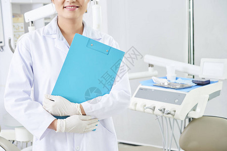 牙科诊所穿着防护手套手持蓝色剪贴板的年图片