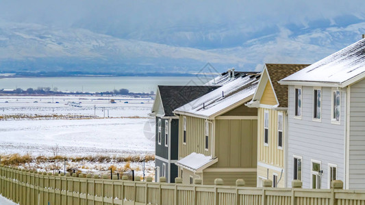 环绕着大片风景覆盖在雪中的木栅栏的全景房屋从远处可以看到湖霜冻山和多图片