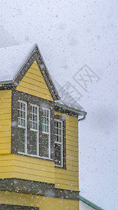 透过落雪观看的垂直雪黄色房屋12月寒冷的冬日图片