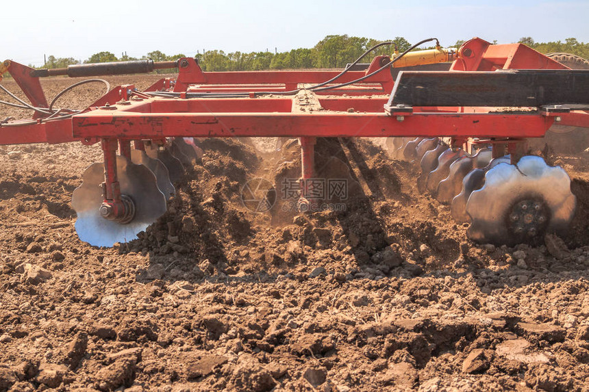 拖拉机用一个耕种者铲开土壤图片