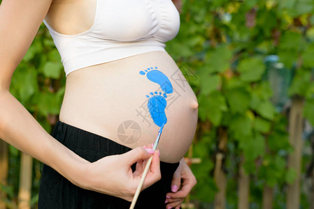 孕妇在肚子上画着牙刷的婴儿足迹怀孕概念图片
