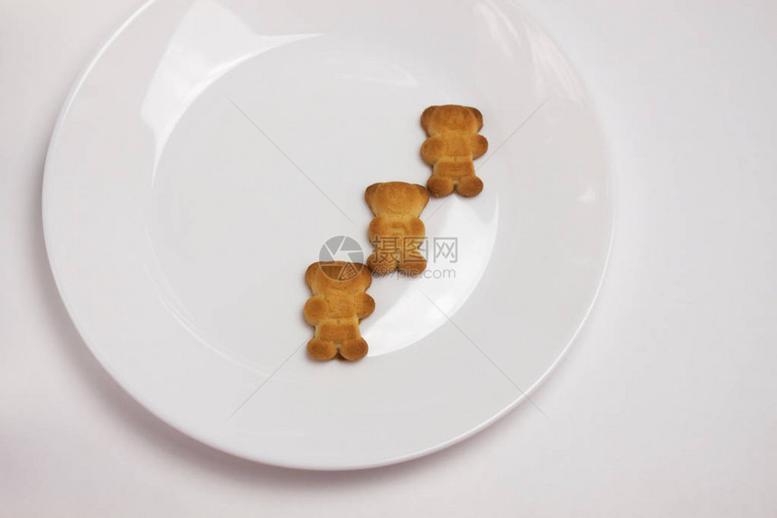 三个可爱的小熊饼干在白色背景上孤立的陶瓷圆板上早餐时间朋友儿童派对餐桌布置庆祝活动从图片