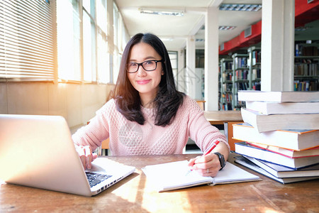 年轻女在图书馆学习时注意到并使图片