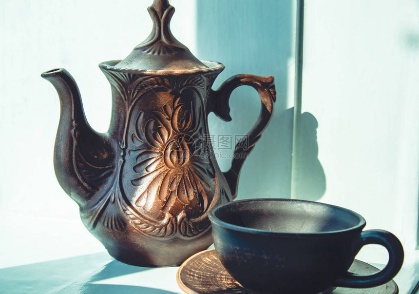 茶壶和粘土杯站在窗户旁图片
