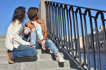 俄罗斯圣彼得堡丰坦卡河堤岸的年轻女士游客一起坐在楼梯上图片