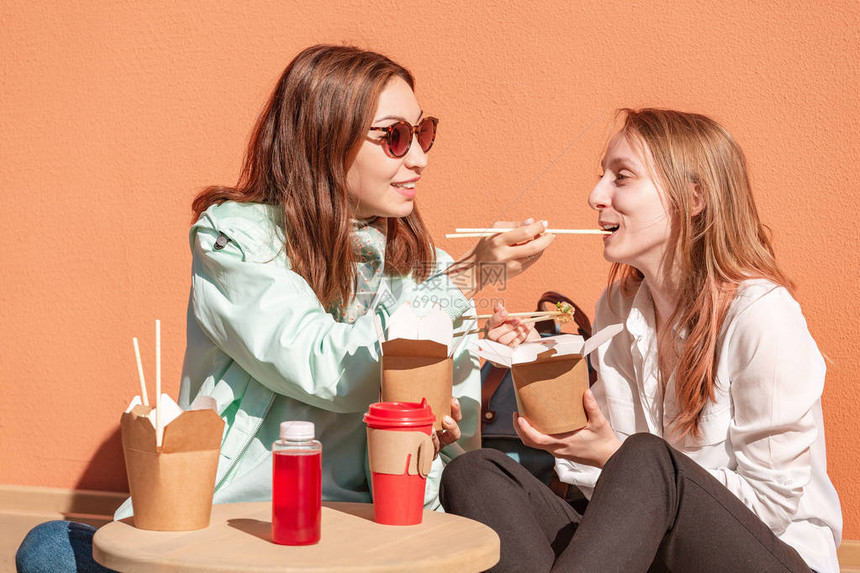 两个女孩朋友在市街的餐馆吃面图片