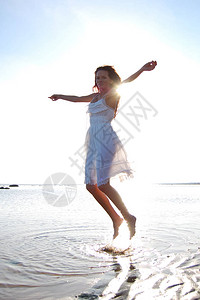 在海边穿着白色太阳裙的年轻苗条女人图片