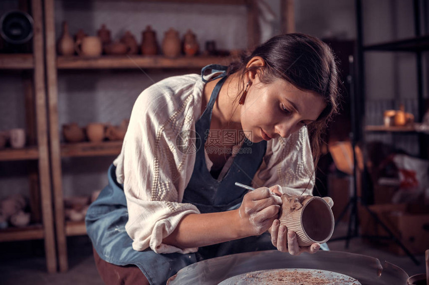 迷人的年轻女主人在轮子上做陶瓷图片
