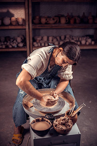 时髦的雕塑家在波特车轮上用粘土工作图片