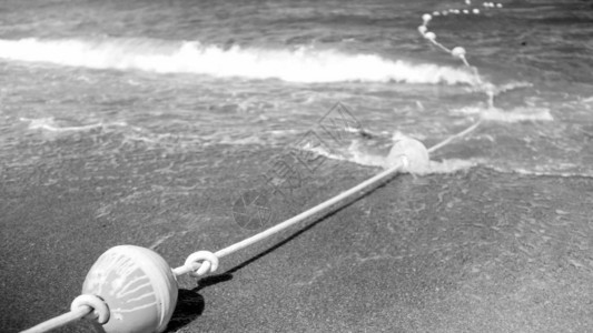 位于沙海滨和水面漂浮的绳索上拯救生命的浮标图片