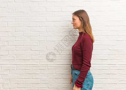 年轻酷女人站在墙边的砖墙图片