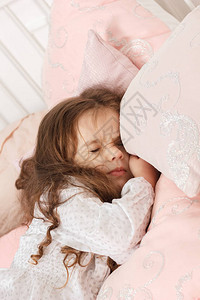 小女孩在家睡在粉红色的床图片