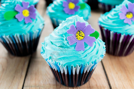 带有蓝色糖霜和紫色花朵的纸杯蛋糕图片