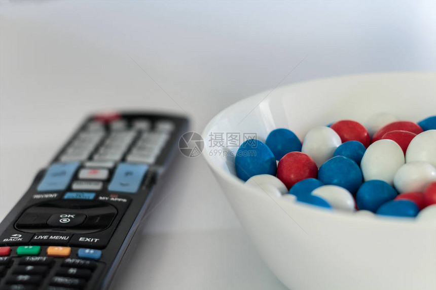 白桌上有红色白色和蓝色糖果拖拉机和电视遥图片