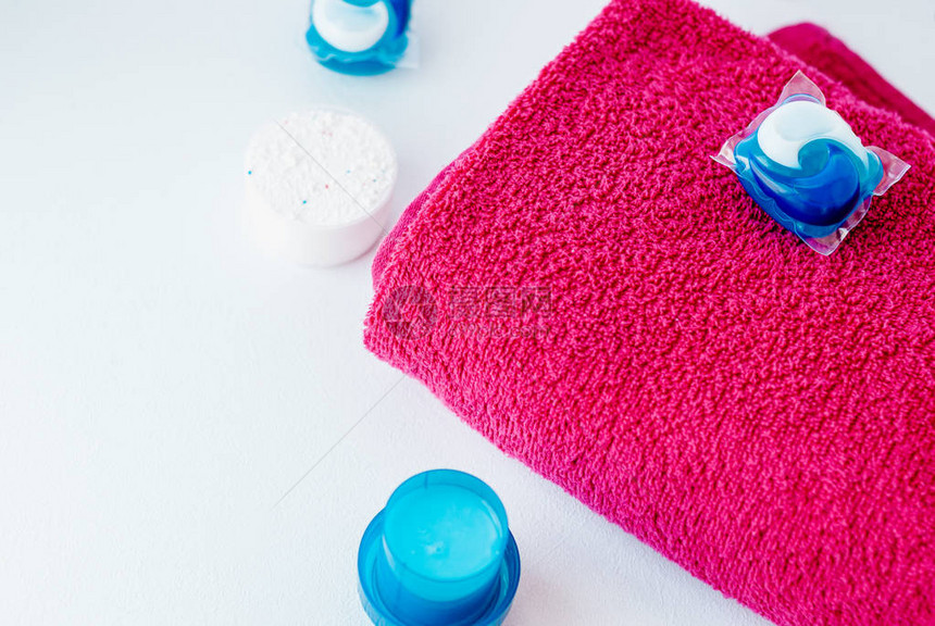 洗涤清洁剂胶囊舱和粉红色毛巾孤图片