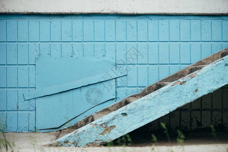 带有舱口和楼梯的建筑物的蓝色墙壁关闭靠着蓝色瓷砖墙的步骤背景与门图片