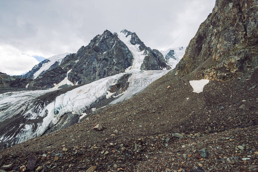 山脉上的雪多云天空下的大气雪脊在阴天的异常巨大的岩石爬上高山高地雄伟自然的图片