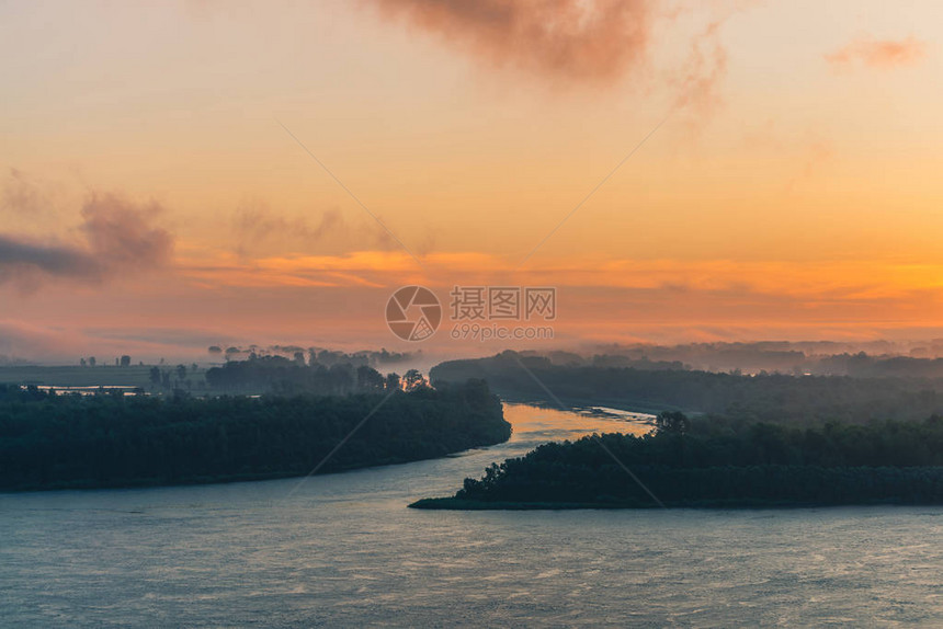 河流沿岸流过雾下的森林河道环绕岛屿流动黎明天空中的橙色光芒映照在水面上五颜六色的早晨神秘大气图片