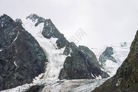 山脉上的雪多云天空下的大气雪脊在阴天的奇妙巨岩爬上高山高地雄伟自然的图片