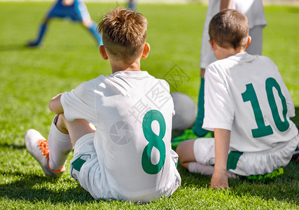 足球学校锦标赛运动场上的一群孩子穿着彩色防滑钉和白色足球套件的足图片