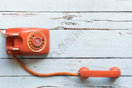旧木制桌子上的回转橙色红线电话图片