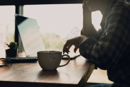 在家线工作或办公桌上放着咖啡杯的兼职在线工作的人模糊图片
