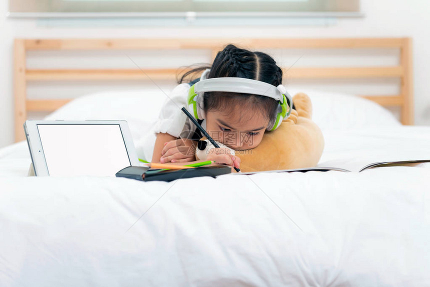 亚洲小女孩对在床上用铅笔写作家庭作业很不高兴图片