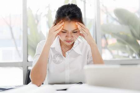 疲惫的亚洲女商人在办公室头痛图片