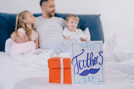 红礼盒和快乐父亲节贺卡的选择焦点在喜悦的男人身边儿子和女儿图片