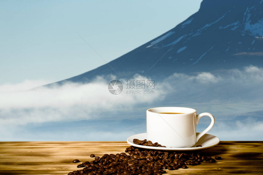 咖啡和白杯放在木制桌子上在冰岛峡湾的雾色风景图片