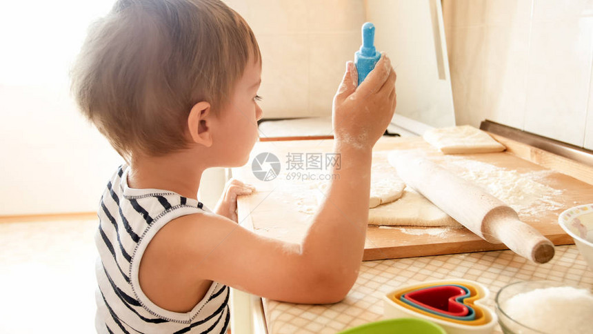 图像岁的蹒跚学步的男孩在木板上滚动面团和烘烤饼干作为早餐孩子在厨房做饭图片