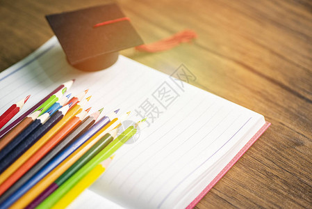 白纸笔记本上的彩色铅笔和毕业上限重新回到学校和教育概念图片