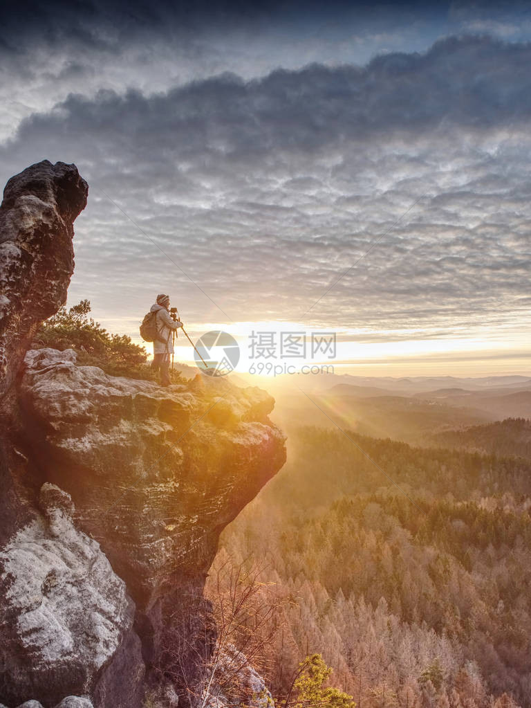 女登山徒和摄影师在深雾谷上的岩石上架设了三脚架图片