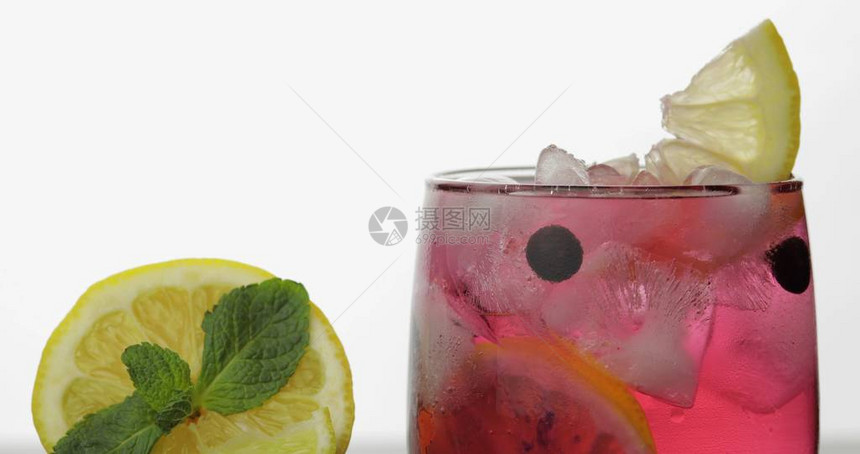 玻璃与冷红色饮料与柠檬黑醋栗和冰块在苏打水中释放气泡和起泡喝在白色背景上的玻璃图片
