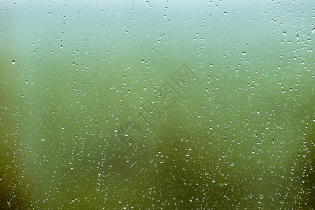 有雨滴的脏玻璃绿色清晰散景背上的雨滴窗外绿意盎然水滴和污渍关闭宏中详图片