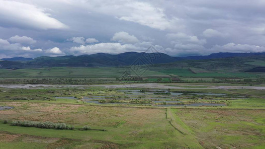 空中绿色的田野和河流山脉在地平线上可见阴天在河边图片