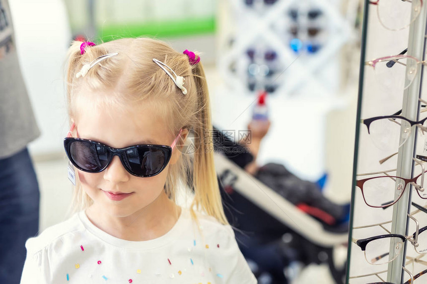 可爱的年轻白种人金发女孩在光学眼镜店的前试戴和选择太阳镜可爱的女学生在商店里戴太阳紫外线防护图片