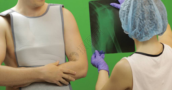 肩膀受伤的男人佩戴用于固定肘关节和肱骨带的绷带前臂肩关节脱位骨折护士检查X射线背景图片