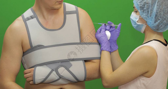 肩膀受伤的男人带注射器的护士用药物使刺痛病人用绷带固定肘关节和图片