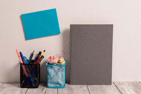 墙上的空粘卡两个网眼铅笔盒灰色精装笔记本背景图片