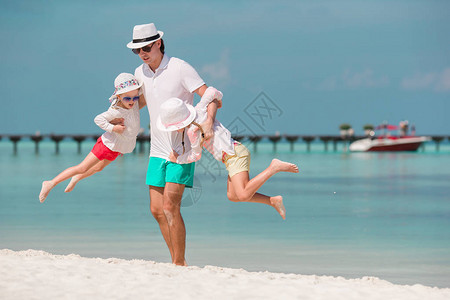 快乐的父亲和可爱的小孩在热带海滩玩得开心图片