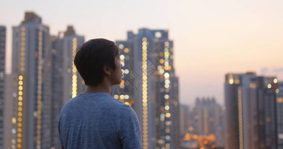男人看夕阳下的摩天大楼图片