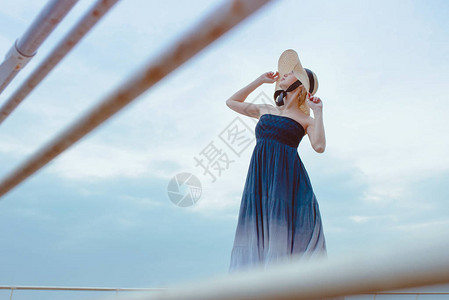 穿着蓝裙子戴着草帽站在海边的白种美丽图片